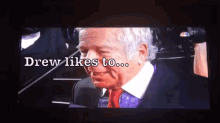 a screen shows a man in a suit and tie with the words drew likes to