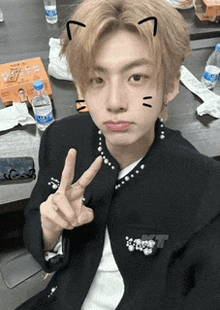 a young man with a cat ear sticker on his face giving a peace sign
