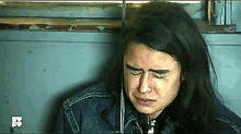 a woman with long hair is crying while sitting in a room with a rope around her neck .