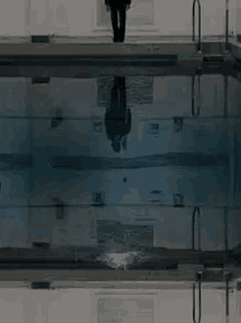 a reflection of a man in a suit in a pool
