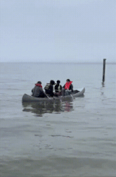 a group of people are in a canoe in the ocean