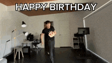 a man in a black shirt is running with a birthday cake in his hand and the words happy birthday behind him