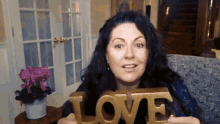 a woman is holding a gold love sign