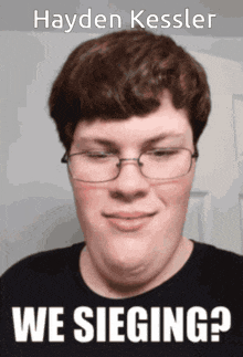 a man wearing glasses and a black shirt with the name hayden kessler on it