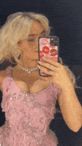 a woman in a pink dress is taking a picture of herself in the mirror