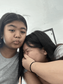 a girl covering her mouth with her hand while another girl makes a funny face