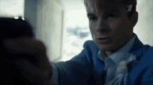 a man in a suit and tie is holding a gun to another man .