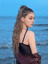 a woman with a braided ponytail is standing on the beach