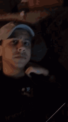a man wearing a hat and a shirt with the letter p on it looks at the camera