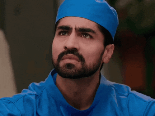 a man with a beard wearing a blue shirt and a blue hat surrounded by white question marks