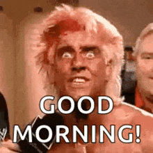 a man with pink hair is talking into a microphone and says `` good morning '' .