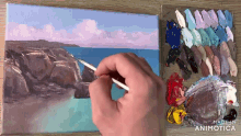 a person is painting a landscape on a canvas with a palette in the background that says made in animotica