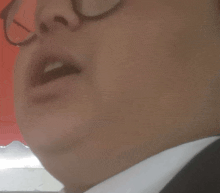 a close up of a man 's face with glasses and a white shirt