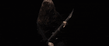 a woman with long hair is playing a guitar in a dark room .