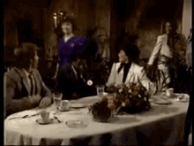a group of people are sitting around a table with plates and glasses