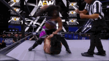 two women are wrestling in a ring that says aew on the wall