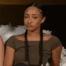 a woman with braids is making a funny face while sitting next to another woman on a bed .