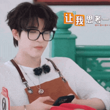 a man wearing glasses and an apron is looking at his cell phone