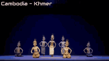 a group of women are dancing in front of a sign that says " cambodia khmer "