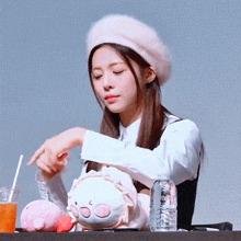 a woman wearing a pink beret is holding a stuffed animal while sitting at a table .