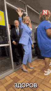 a woman in a blue suit is waving in front of a man in a suit