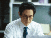 a man in a white shirt and tie is looking down
