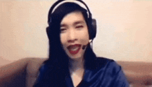 a woman wearing headphones and red lipstick is sitting on a couch and smiling .