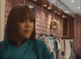a woman in a green robe stands in front of a row of clothes hanging on racks