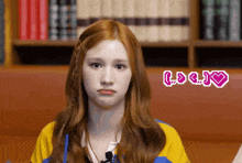 a girl with red hair is making a funny face with a heart and the word love behind her
