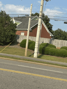 a telephone pole is leaning over the side of the road in front of a brick house