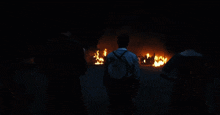 a man wearing a backpack stands in front of a fire