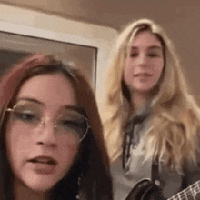 two young women are standing next to each other playing guitars .