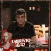 a man in a black shirt is standing in front of a mirror in a room .