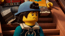 a lego character wearing a blue helmet and a blue shirt with the letter m on it