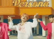 a group of young men are dancing in front of a building that says persona