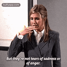 a woman in a suit is covering her mouth with her hand while crying .