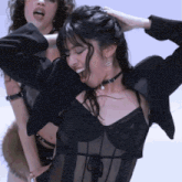 a woman in a choker is dancing with another woman in a black outfit