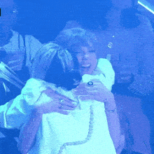 a woman in a white shirt is hugging another woman