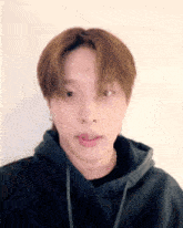 a close up of a young man wearing a black hoodie making a funny face .