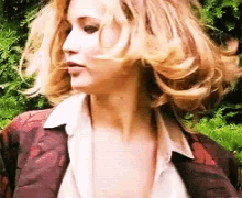a woman with blonde hair wearing a white shirt and a red jacket