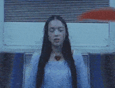 a woman with long hair is sitting in a chair with her eyes closed and a heart necklace .