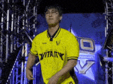 a young man wearing a yellow shirt and glasses is standing in front of a stage .