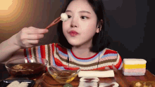 a woman is eating food with chopsticks and a bowl of liquid