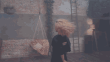a woman in a black dress is standing in front of a brick wall