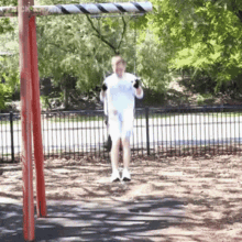a man is swinging on a red and white swing set