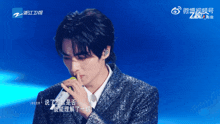 a man singing into a microphone with chinese writing on the bottom