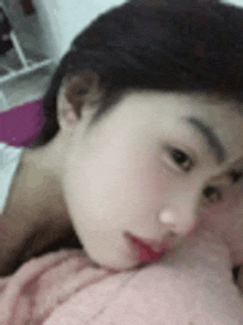 a close up of a woman 's face with a pink blanket covering her face .