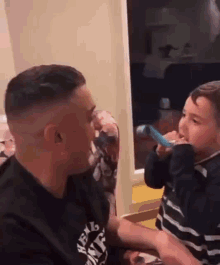 a man is brushing his teeth with a child while holding a toothbrush .
