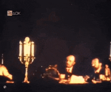 a group of people are sitting at a table with candles and a sign that says 24 aok on it