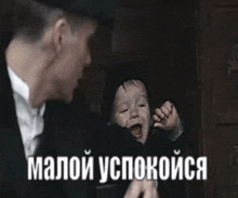 a man in a suit is holding a baby in his arms in a dark room .